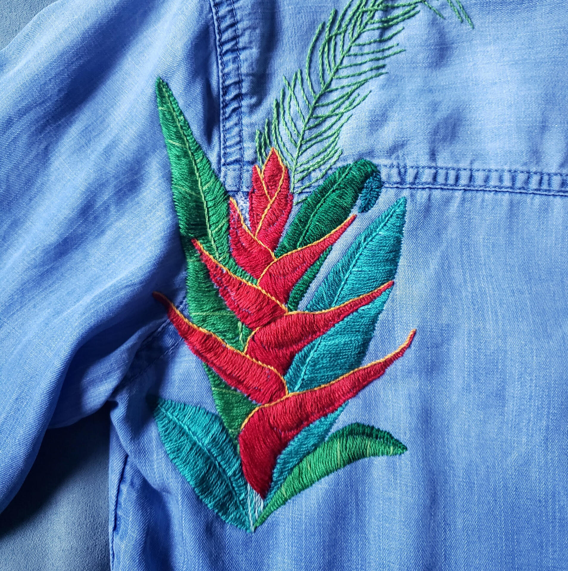 Hand embroidered tropical flowers embellish and cover a tear